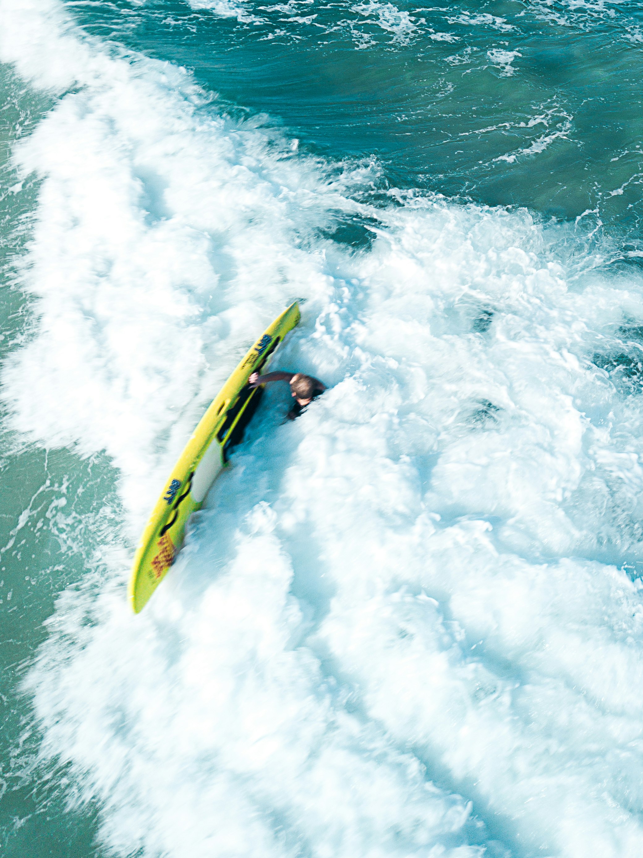 person swimming on ocean and holding surfboard