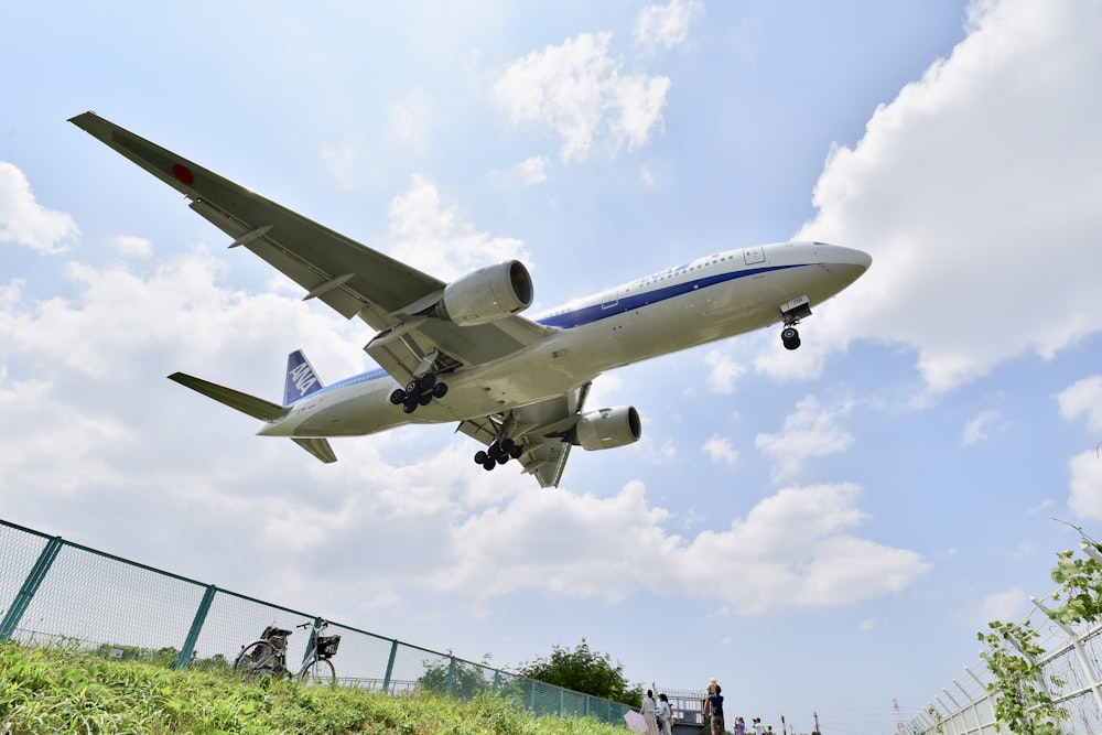 white and blue plane flying above people during daytime