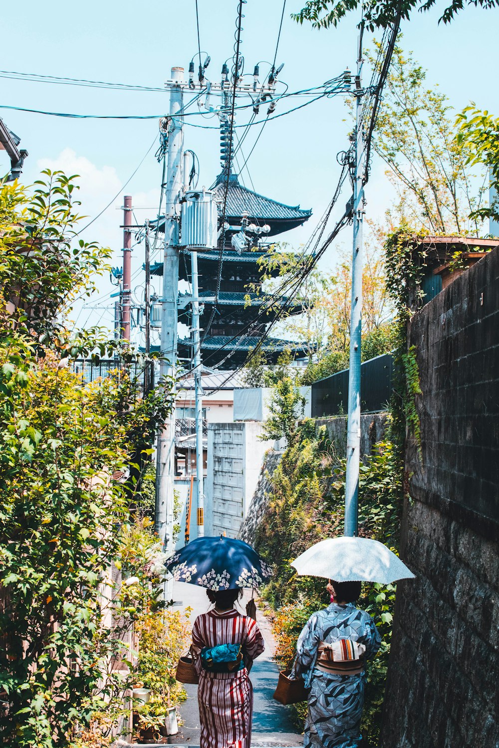 a couple of people walking down a street holding umbrellas