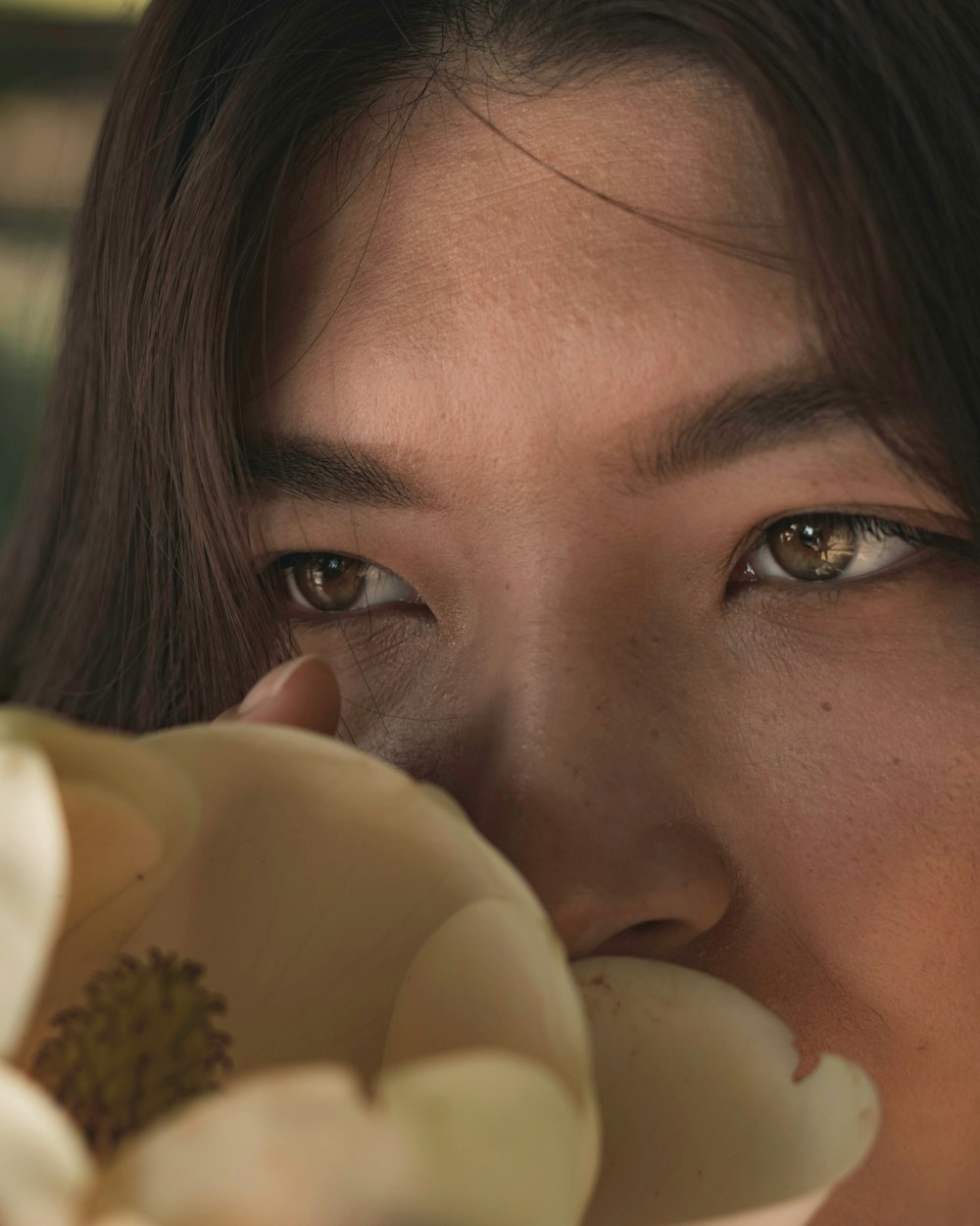 woman sniffing white flower