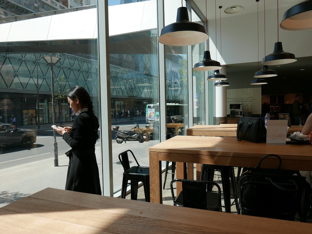 standing woman wearing black coat using smartphone