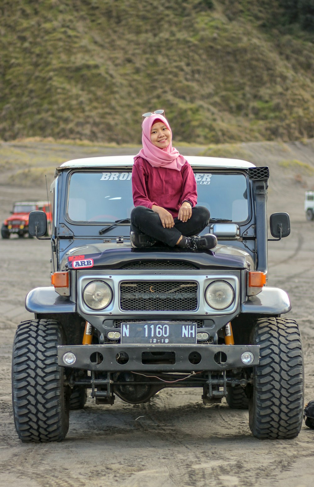 women's pink hijab sitting on white vehicle close-up photography