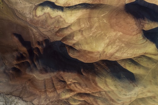 Moody editorial shot of layered earth textures blending into a cultural site