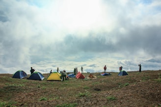 Wide shot of a group camping with multiple float tents pitched on a sloped hillside