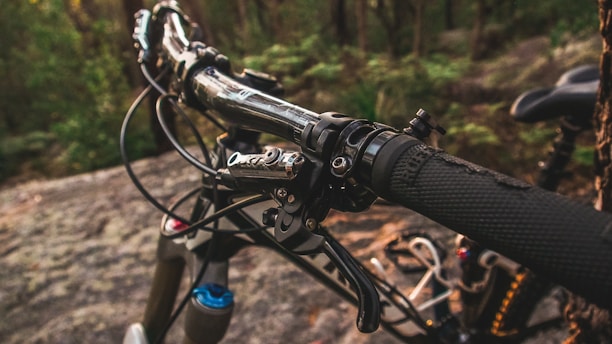 Close-up of our cycling gloves gripping a vibrant mountain bike handlebar outdoors.