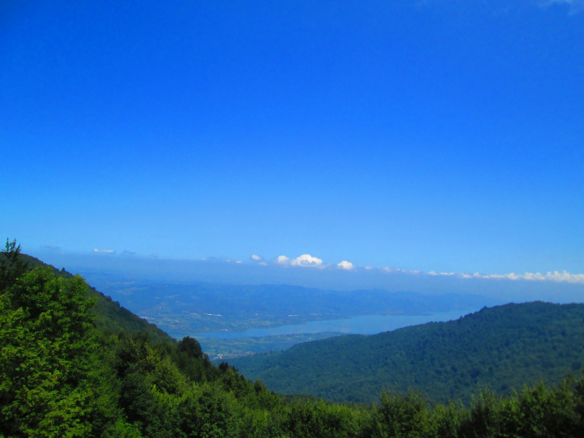 A panoramic view of a serene natural landscape featuring rolling hills and a clear blue sky.