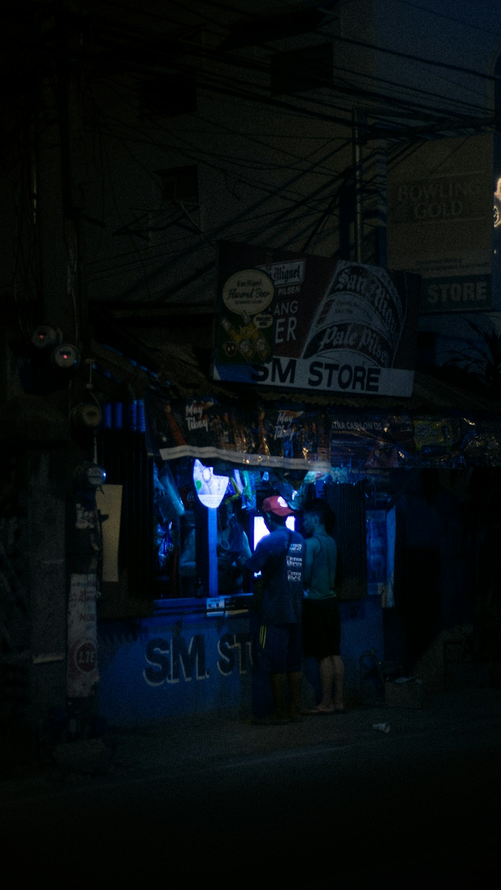 a group of people standing outside of a store at night