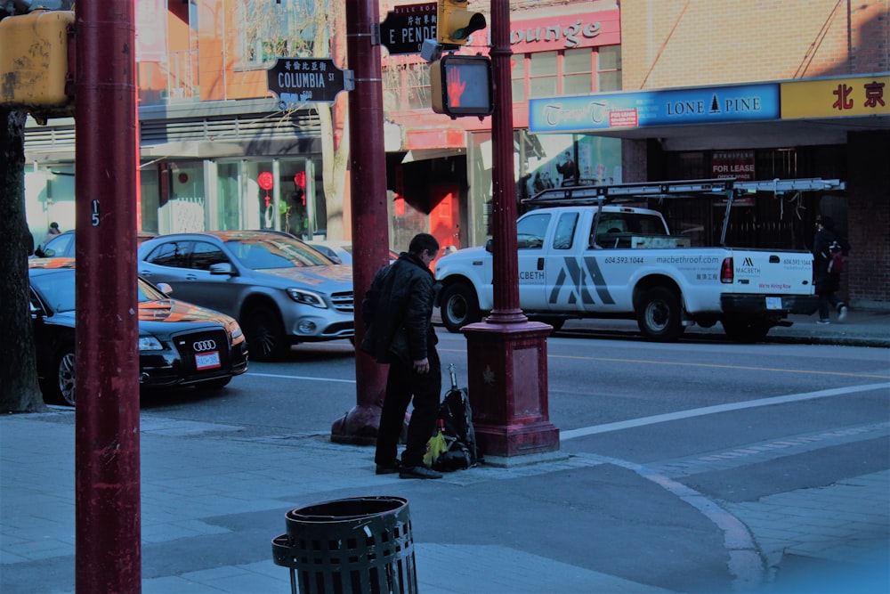 man standing near metal post on street