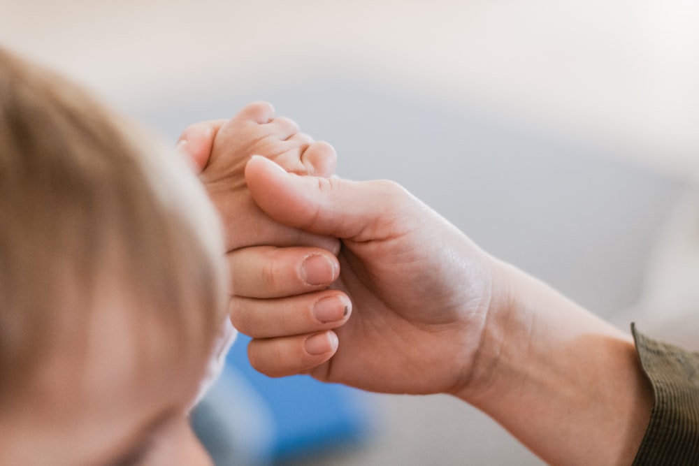 a close up of a person holding a child's hand