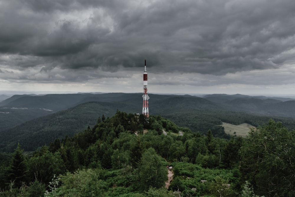 Torre branca e vermelha na montanha sob céus brancos e cinzentos