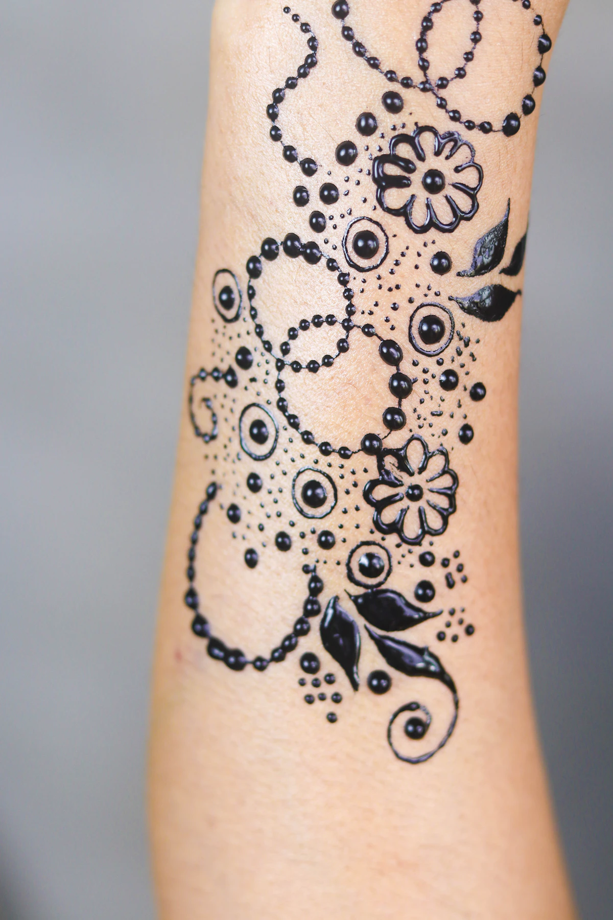Delicate black floral arm tattoo