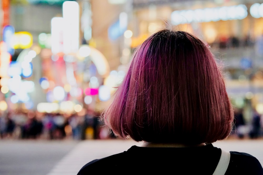 後ろを向いている紫色のリンゴカットの髪の女性