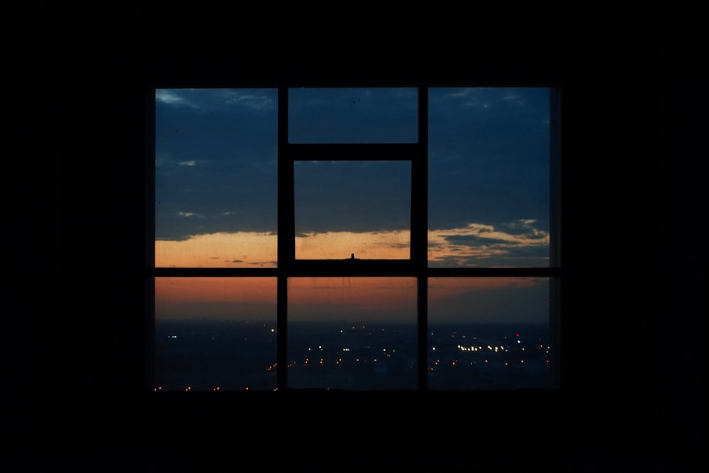 Fotografia da silhueta da vista da cidade de uma janela de vidro