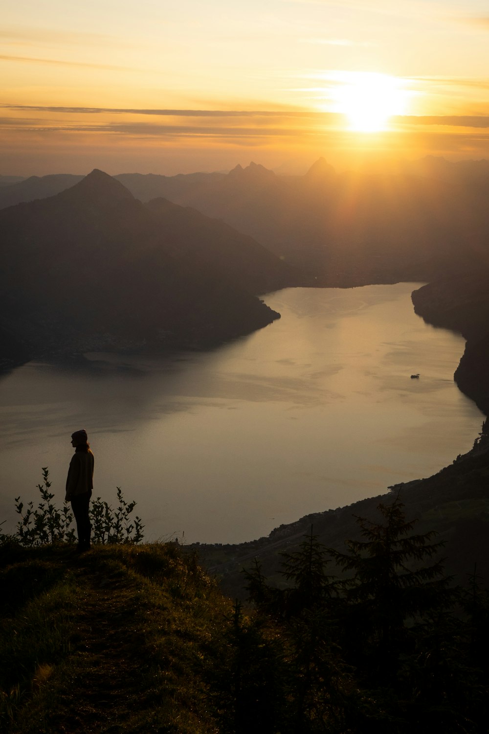 Una persona parada en la cima de una colina con vistas a un lago