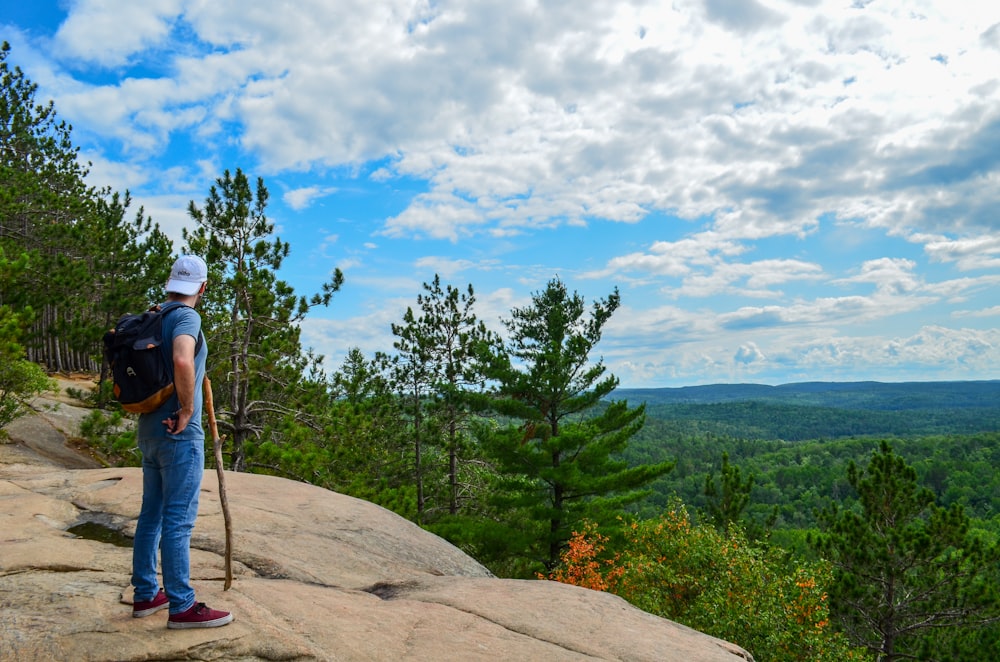 man wearing blue shirt and blue denim jean standing near trees during daytime