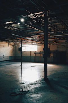 Photo showing a dim, empty basement space with exposed beams and concrete surfaces.
