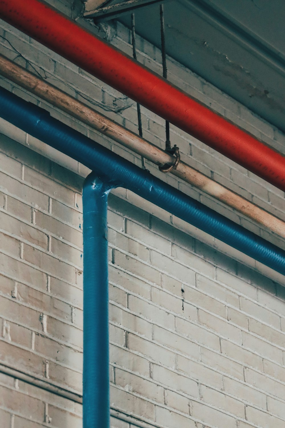 a red and blue pipe on a brick wall