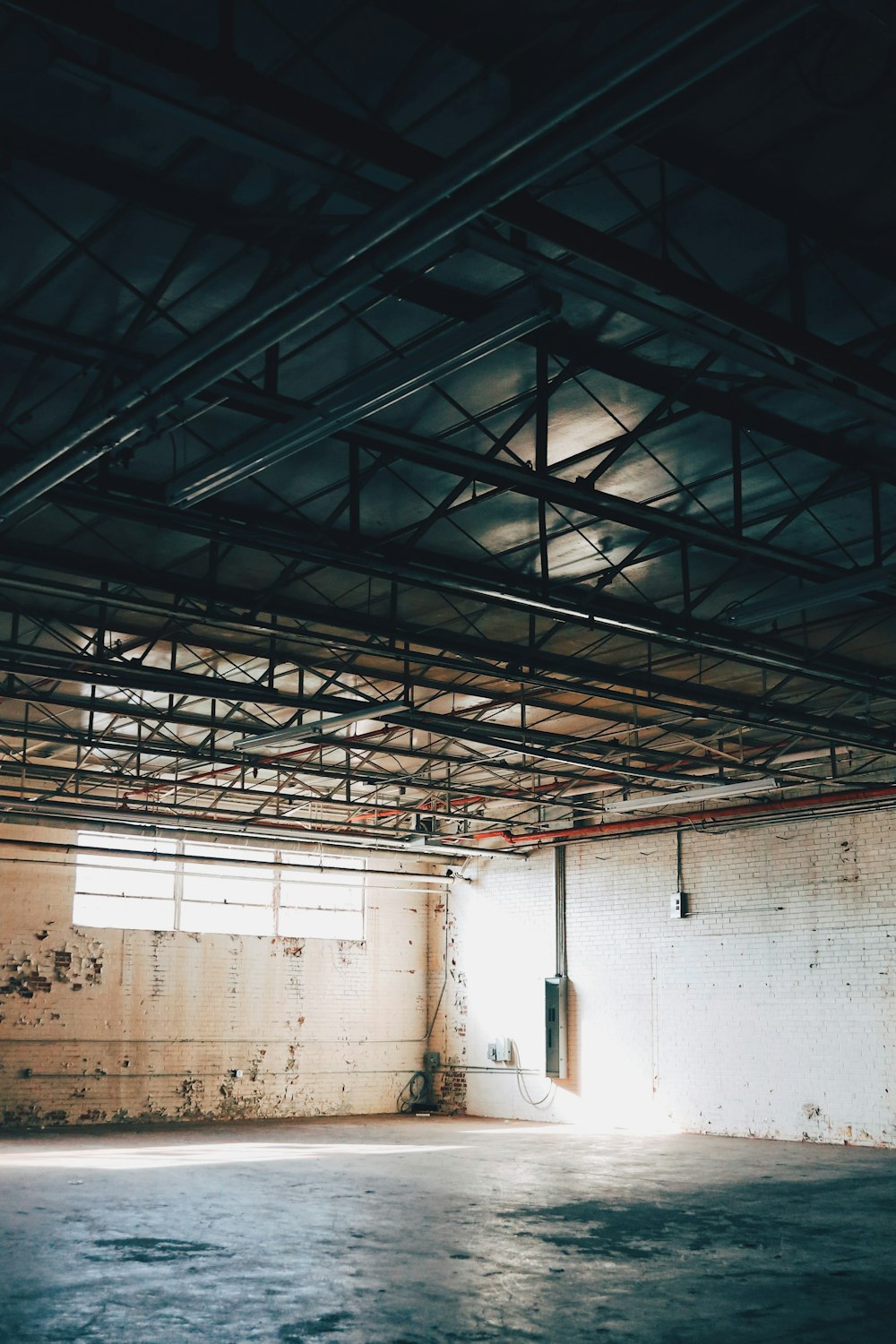 an empty room with exposed pipes and a door