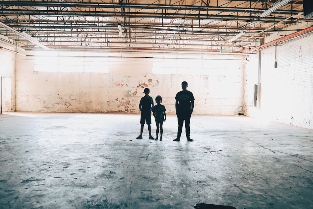 three people standing inside an empty building