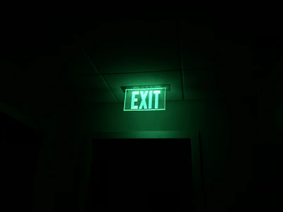 Emergency exit sign illuminated brightly in a dim hallway.