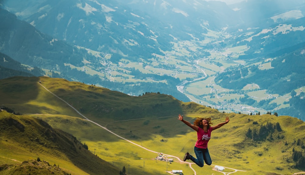 woman jumping on hill during daytime