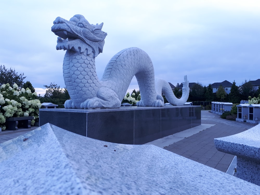 white dragon statue near flowers during day