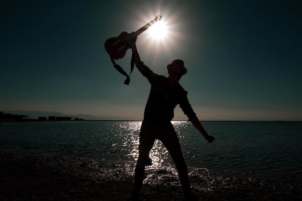 Persona sosteniendo la guitarra en la fotografía de la silueta