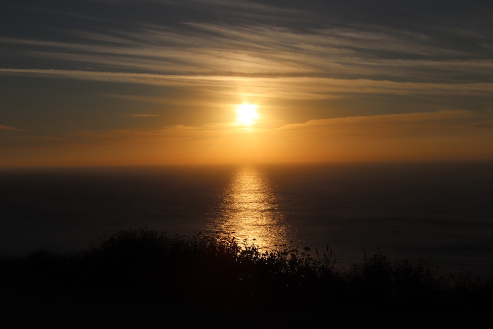 Il sole sta tramontando sull'oceano in una giornata nuvolosa