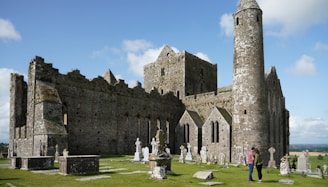 people standing near brown castle under blue sky and white clouds