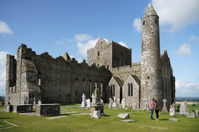 people standing near brown castle under blue sky and white clouds