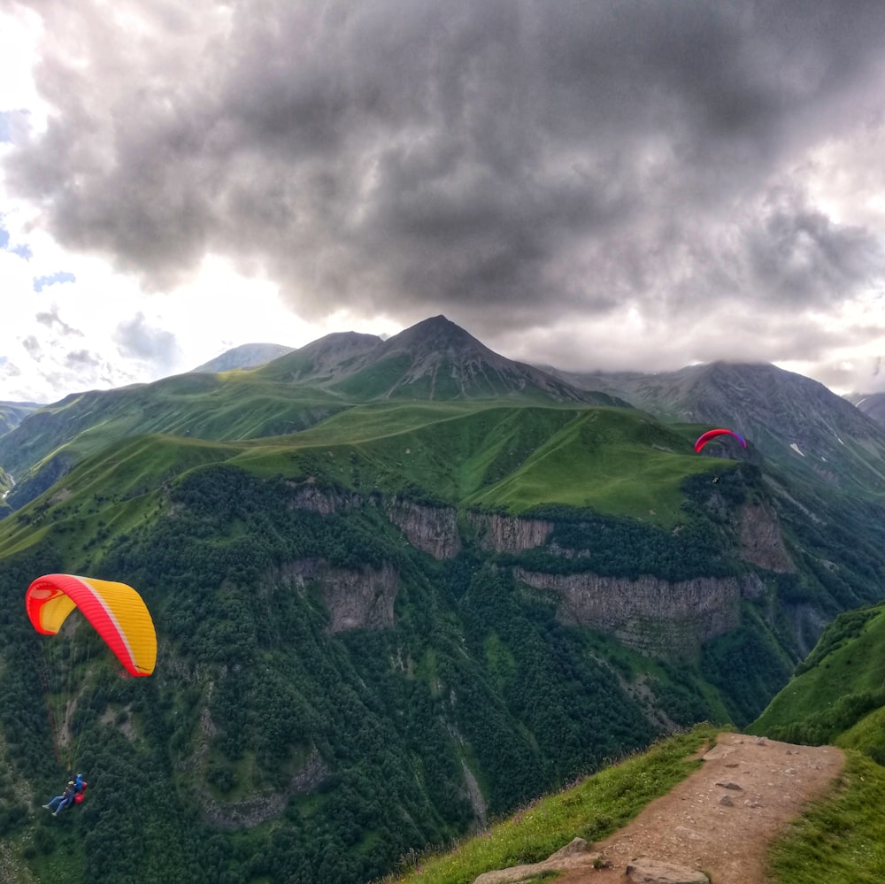 two person doing paragliding over the mountain