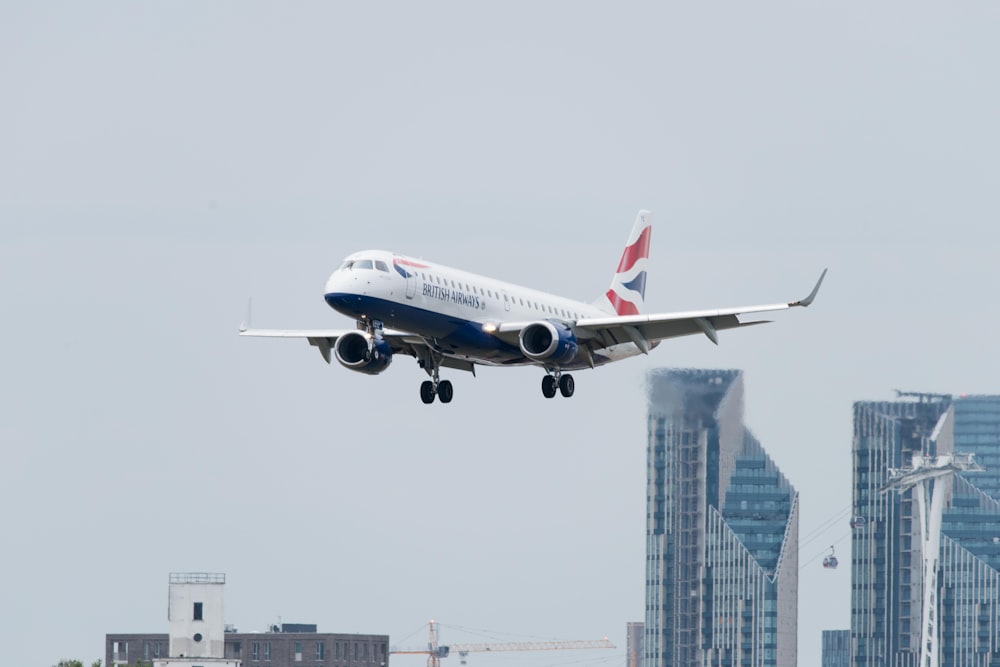 white, red, and blue airplane above buildings