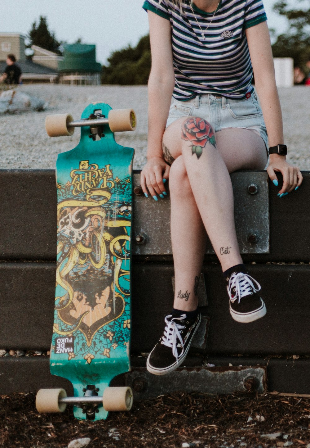 girl wearing green and white stripe shirt sitting besides green longboard