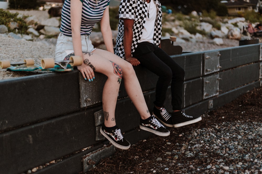 two person sits on fence