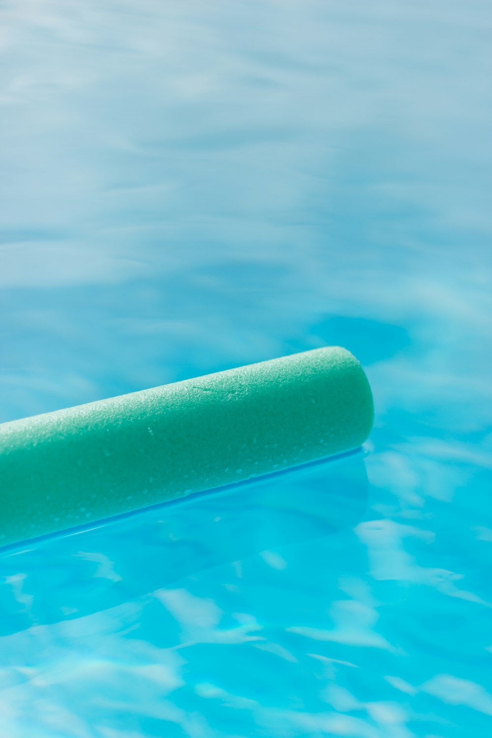 a green tube floating in a pool of water
