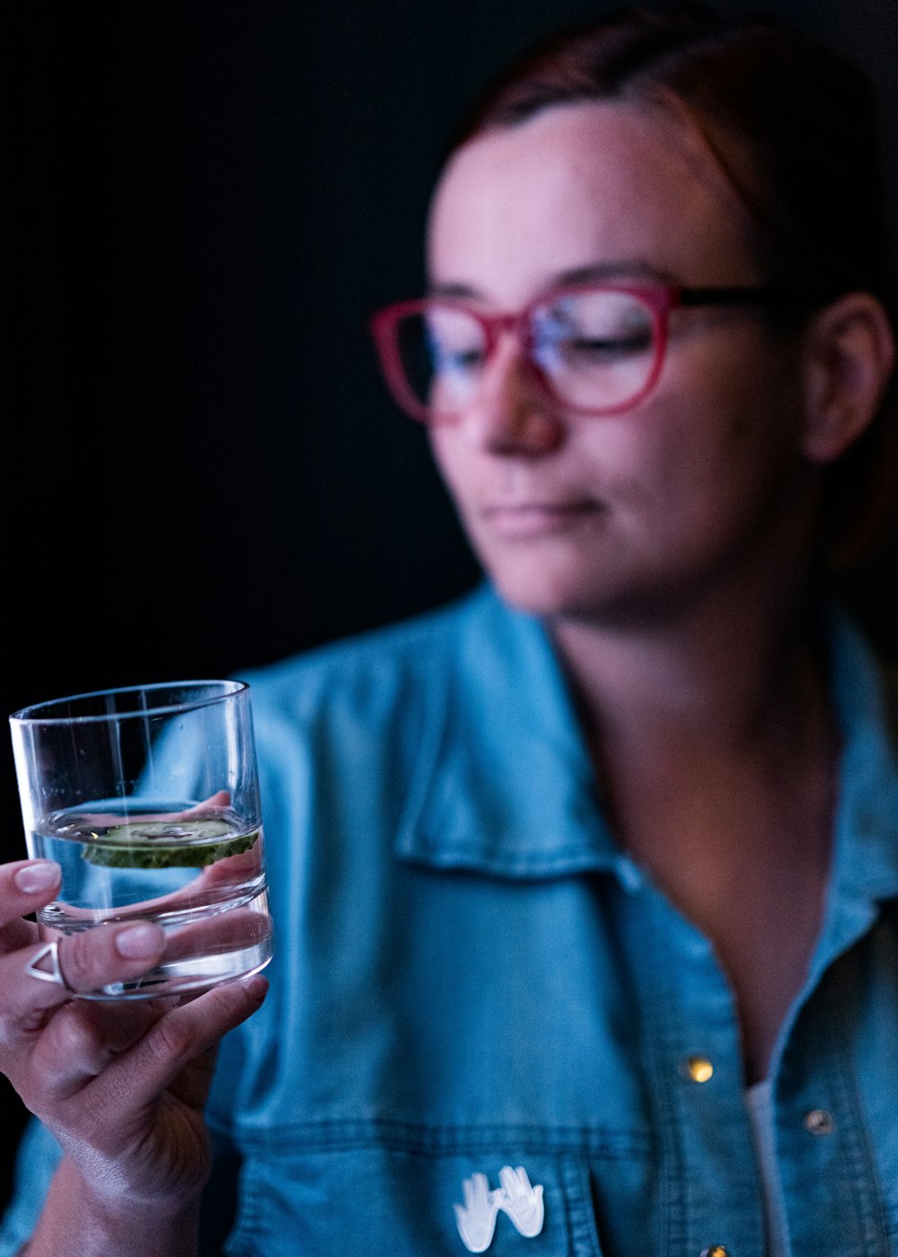 a woman wearing glasses holding a glass of water