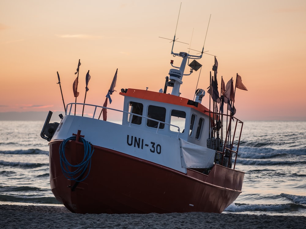 a red and white boat sitting on top of a beach