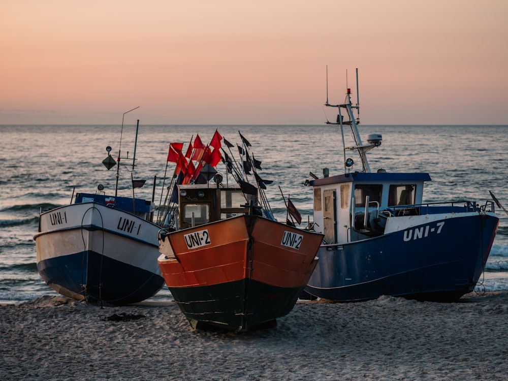 three blue, white, and red fishing vessels on seashore