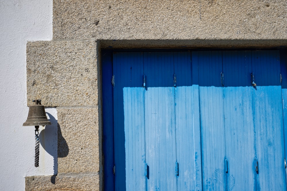 a blue door with a bell on the side of it