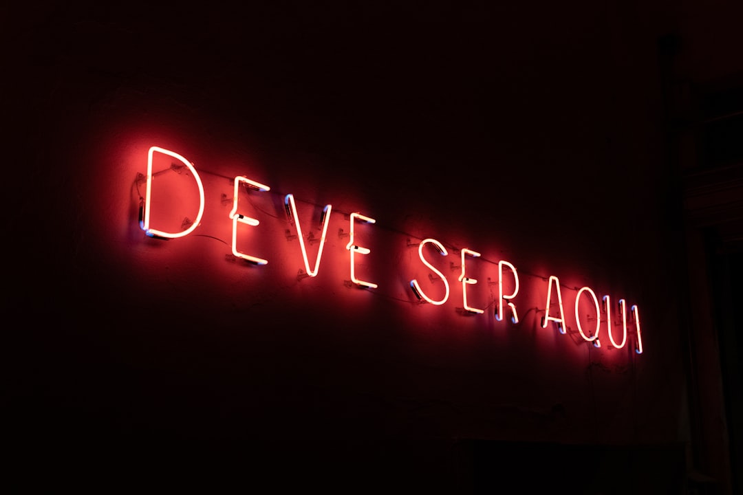 Neon sign at the entrance of a restaurant in São Paulo where it reads "deve ser aqui" ("it must be here")