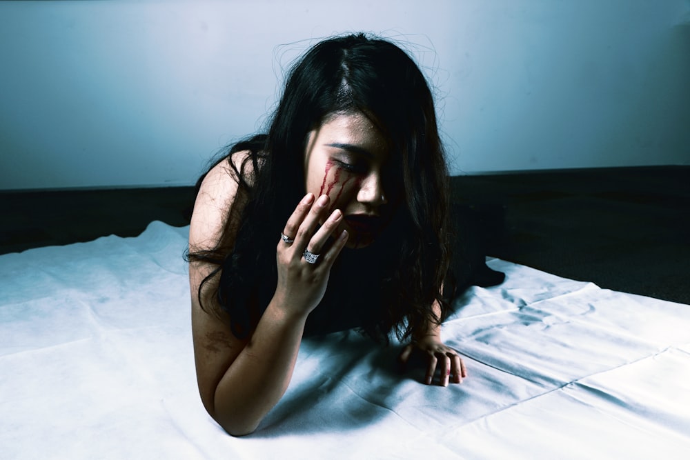 woman crying with red blood prawn lying on bed