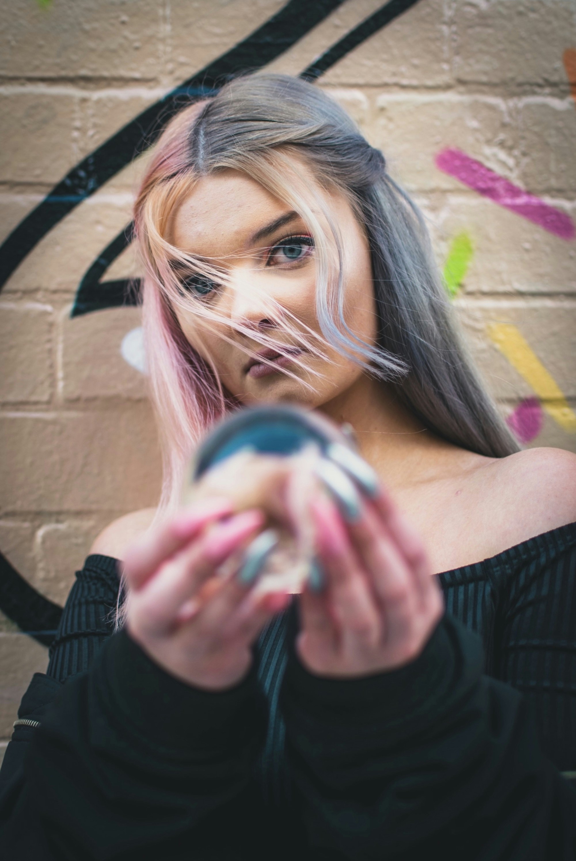 wanita mengenakan blus lengan panjang off-shoulder hitam memegang bola kecil bening