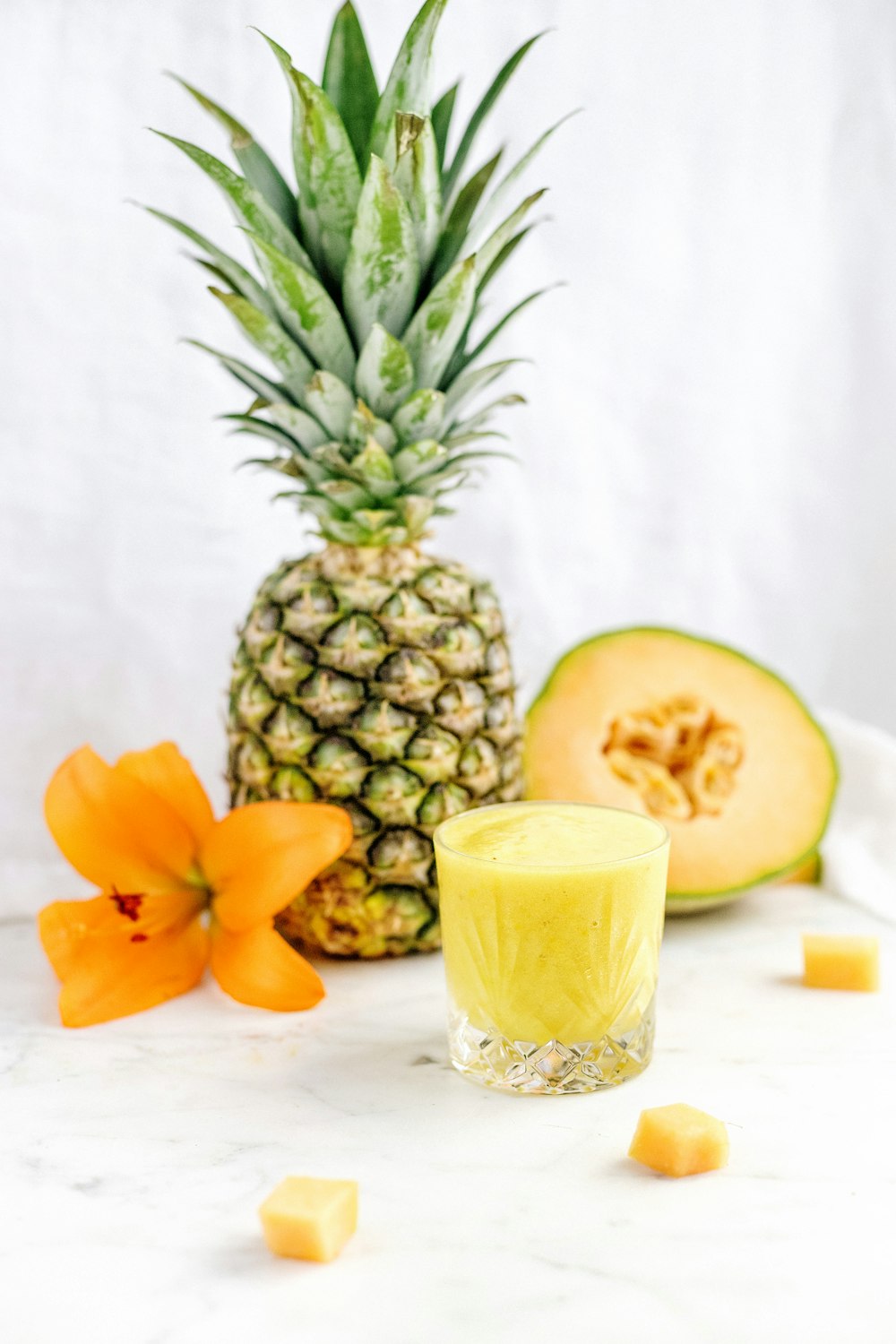 pineapple fruit beside orange petaled flower