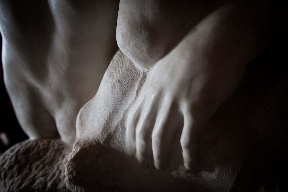 un primo piano delle mani di una persona su una statua