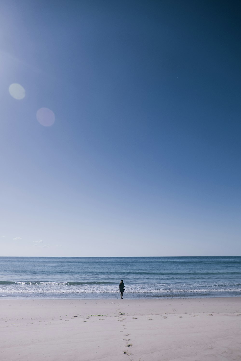 eine Person, die an einem Strand neben dem Meer steht