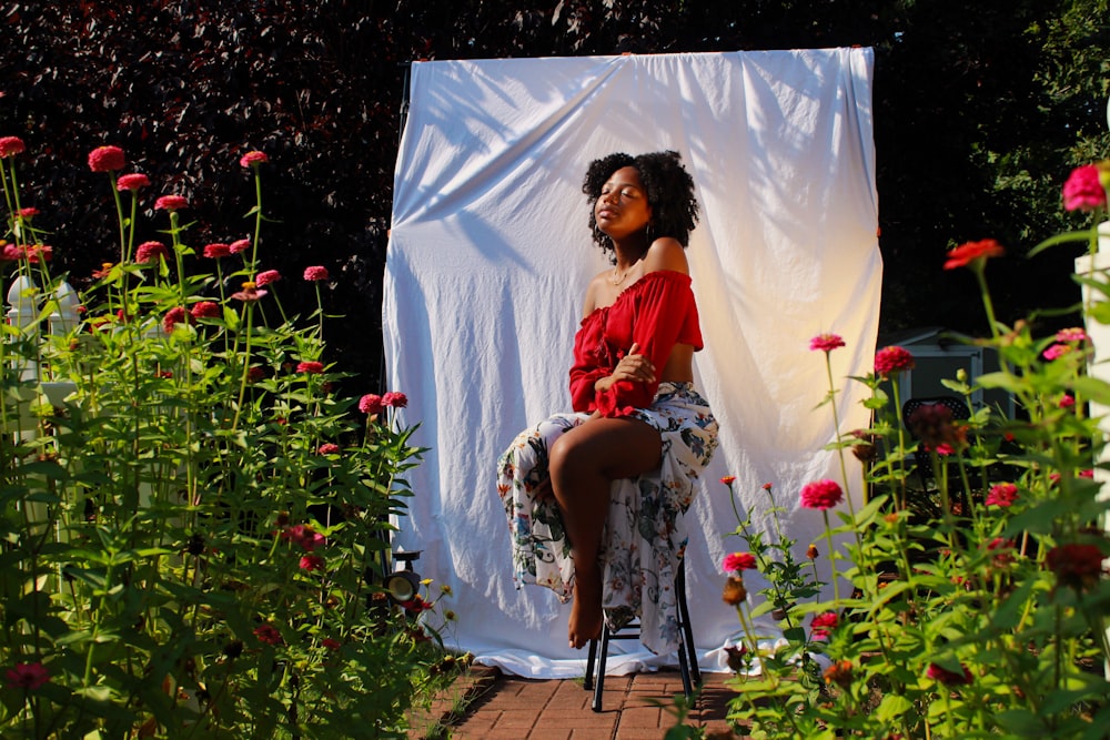 woman sitting on stool surrounded with red flowers