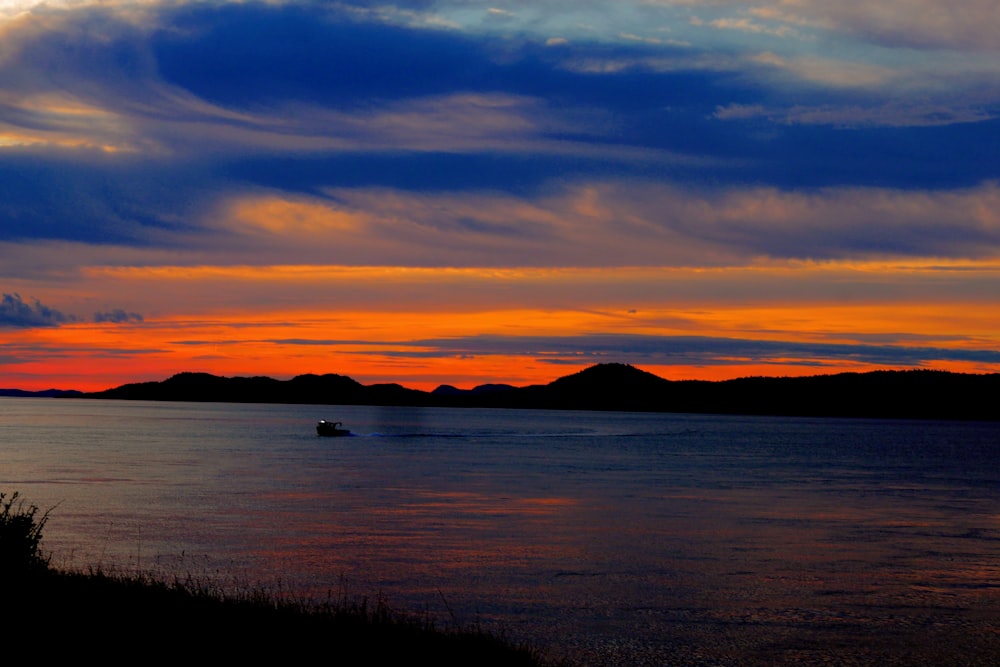 body of water near mountain at golden hour