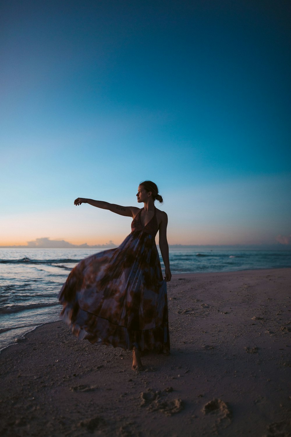 women's white and brown floral long dress standing beside body of water during golden hour