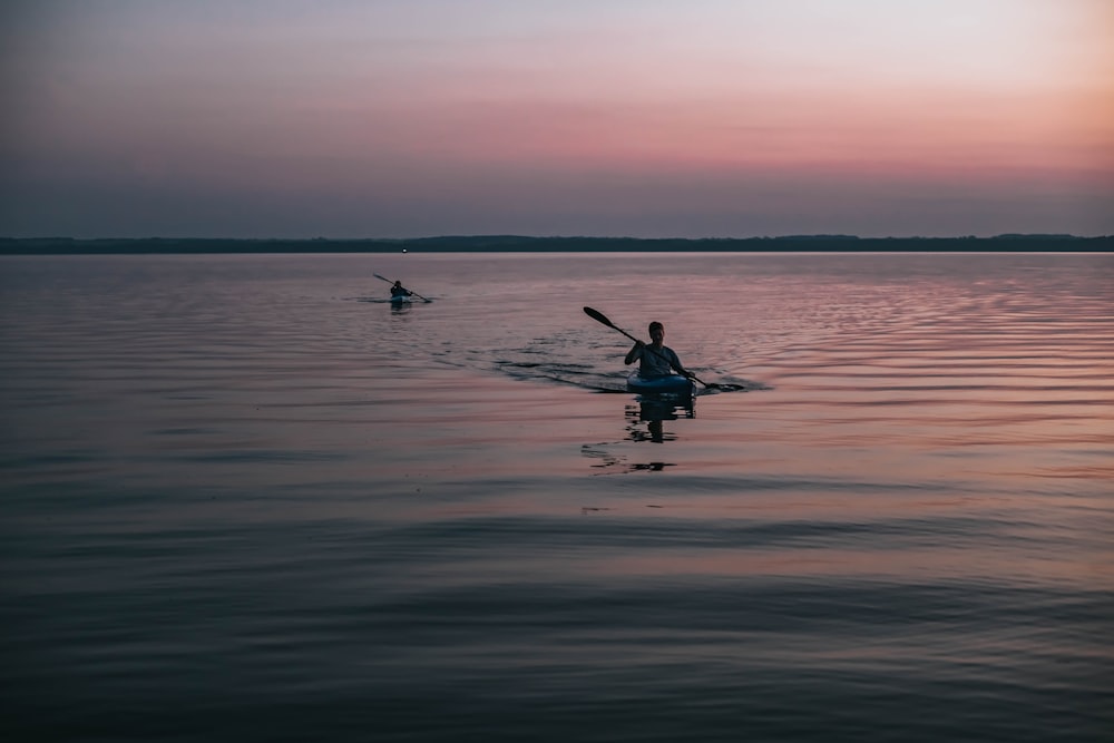 silhouette of person riding kayak