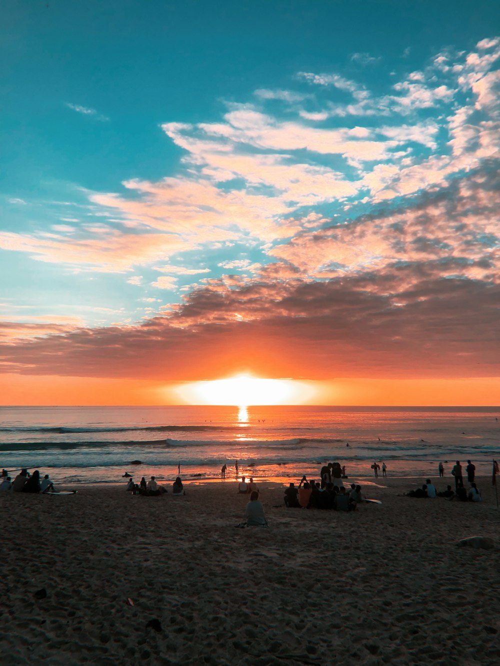 Gente en la playa durante la puesta de sol